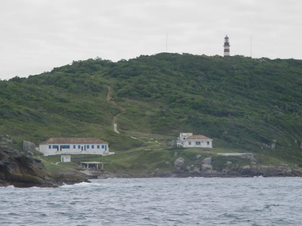 Farol do Arvoredo de ferro fundido com faixas brancas e vermelhas ao lado da base da Marinha do Brasil