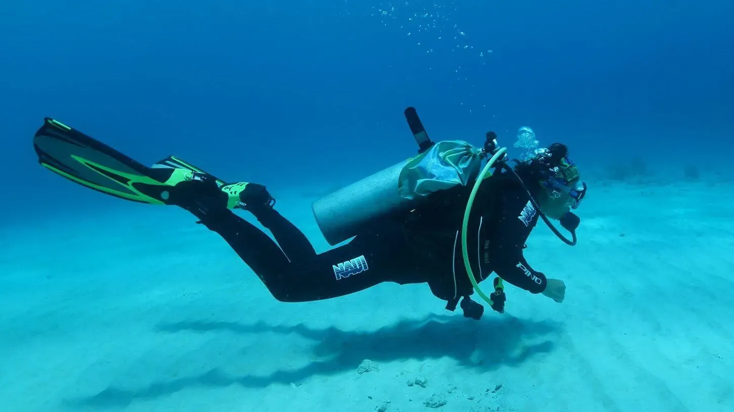 Mergulhador NAUI deslizando sobre o fundo arenoso em mar aberto