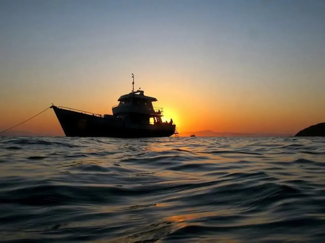 Embarcação de mergulho Acquanauta em silhueta ao pôr do sol