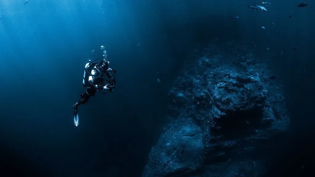 Mergulhador junto a uma parede submersa em águas profundas