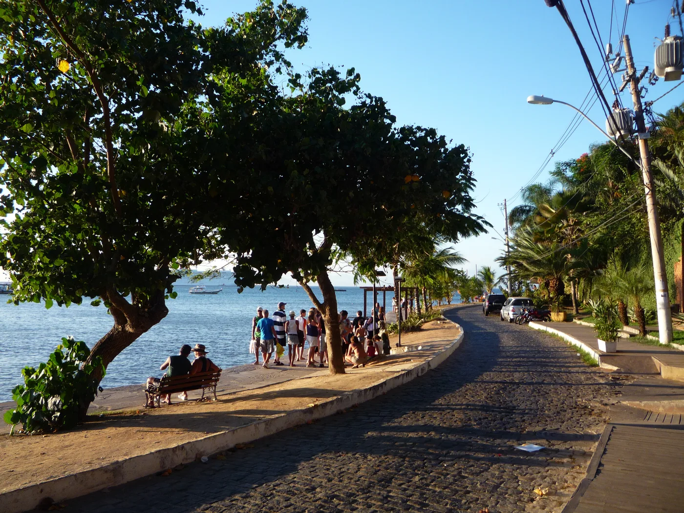 Orla Bardot, em Búzios: calçadão à beira-mar sob árvores, com pessoas passeando