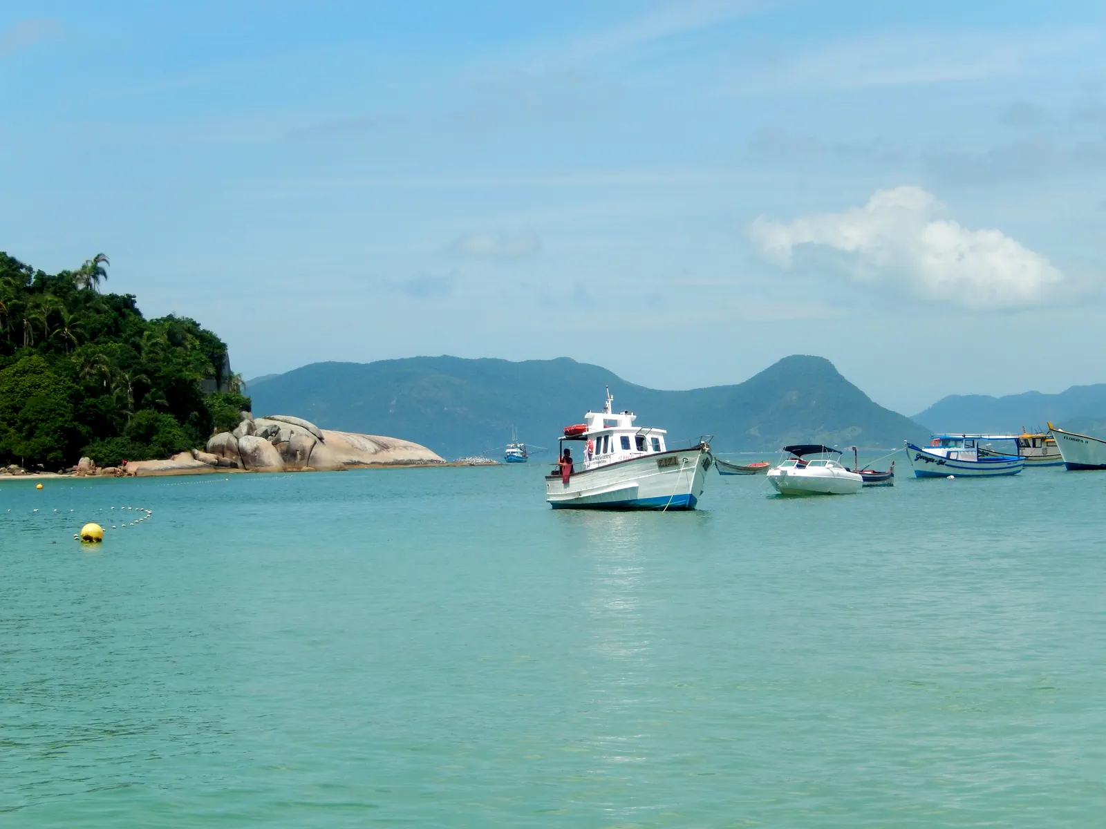 Barcos em frente à Ilha do Campeche, com o costão e os morros de Florianópolis ao fundo
