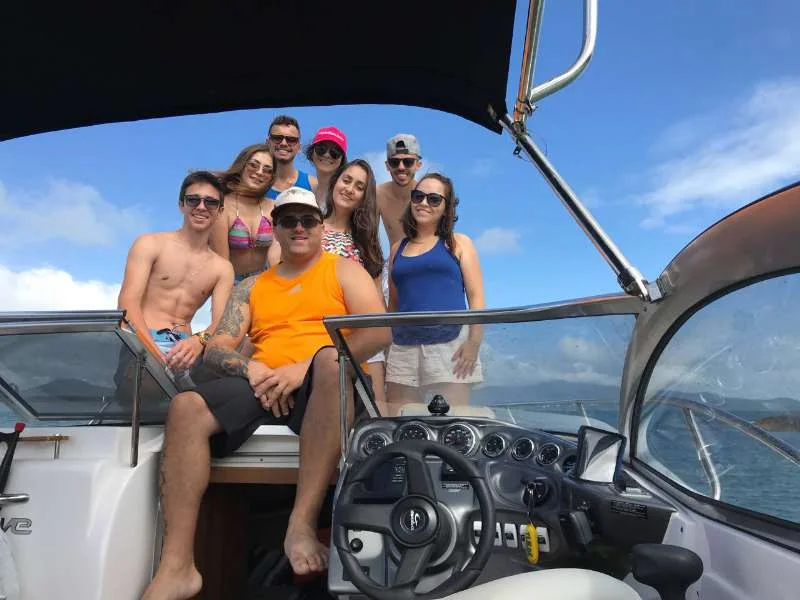 Grupo de oito amigos reunido na lancha, sorrindo para a foto