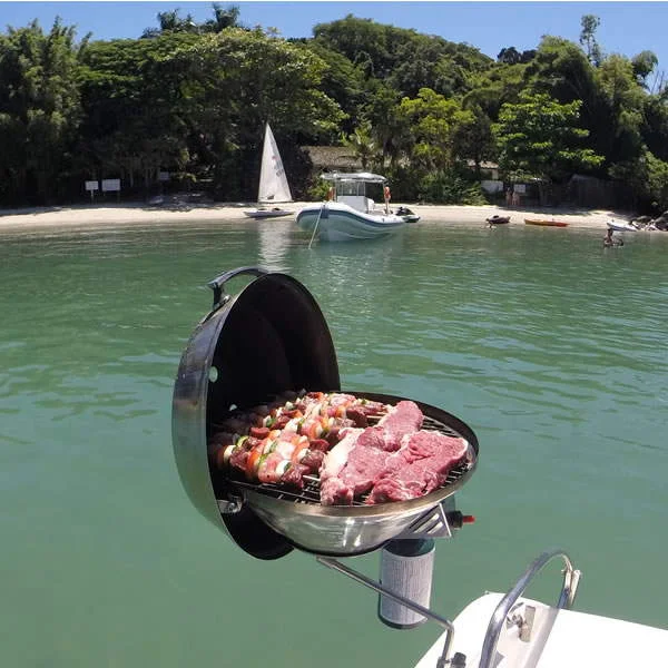 Churrasqueira da lancha com carne e linguiça assando, água verde ao fundo