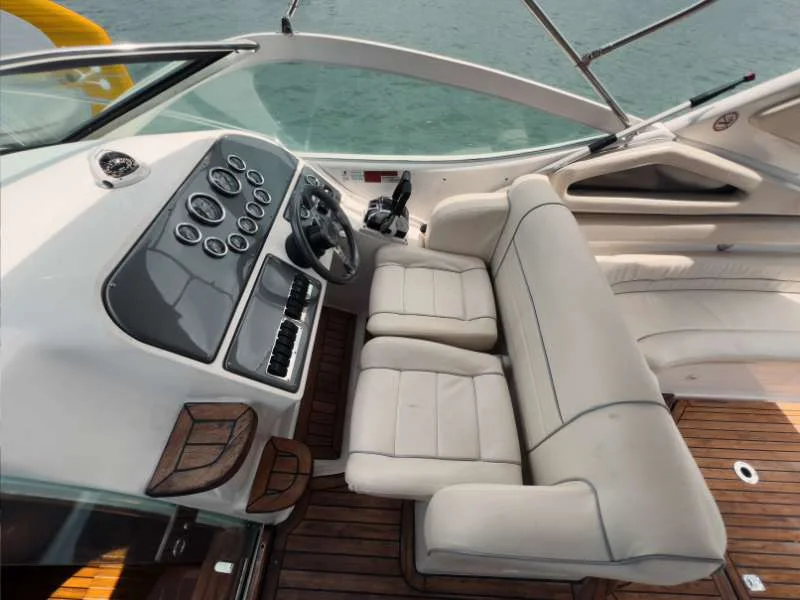 Cockpit da lancha com painel, sofá em couro claro e deck de madeira