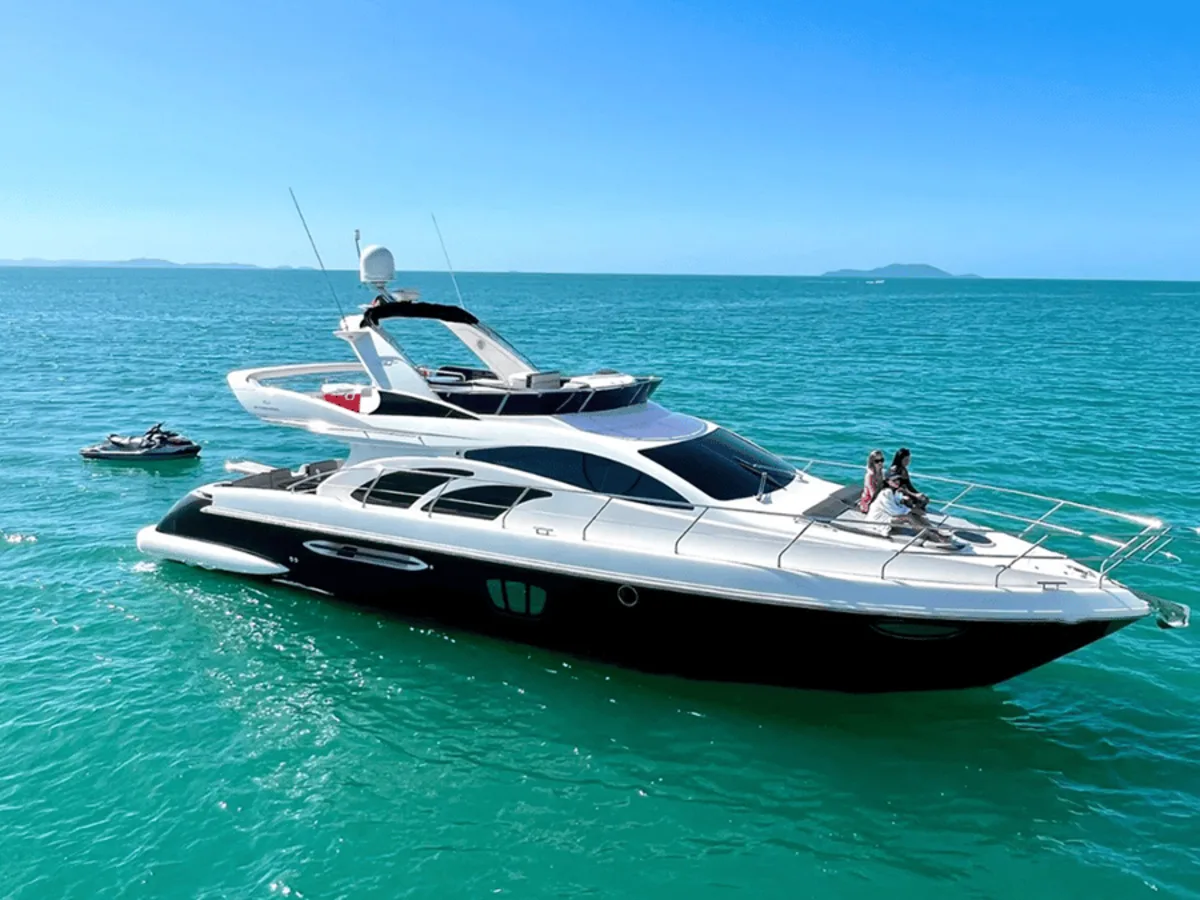 Iate com flybridge em água turquesa com passageiros na proa