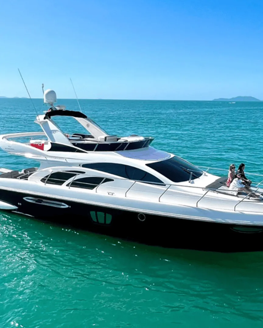Iate com flybridge em água turquesa com pessoas na proa