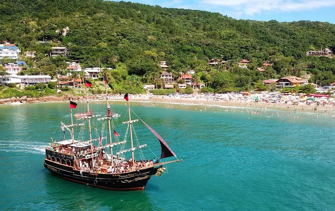O barco pirata navegando diante de uma praia do Norte da Ilha