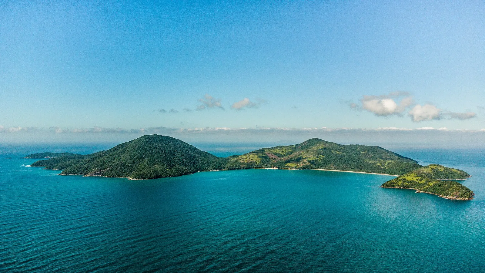 Vista aérea da Ilha Anchieta em Ubatuba, coberta de mata e cercada por mar azul-turquesa
