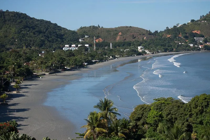 Vista do alto da Praia da Enseada em Ubatuba, com a faixa de areia curva e o mar calmo
