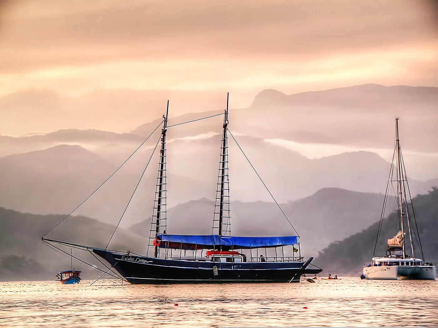 Embarcação ancorada ao entardecer em Ubatuba, com a serra em camadas ao fundo