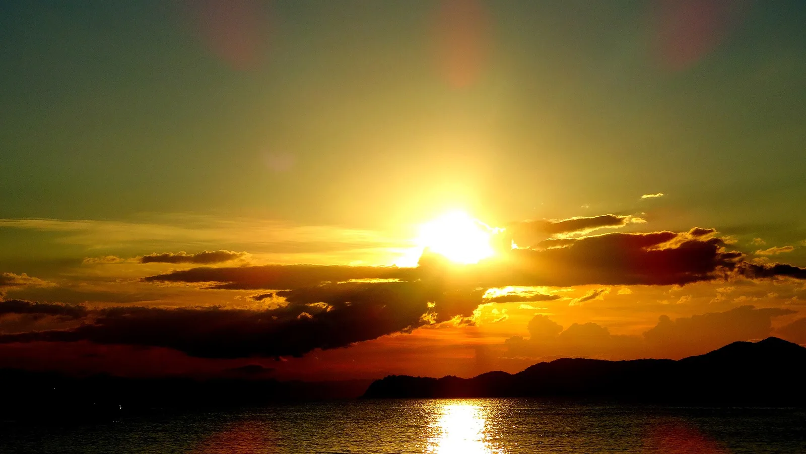 Pôr do sol alaranjado sobre o mar em Ubatuba, com a silhueta das ilhas no horizonte