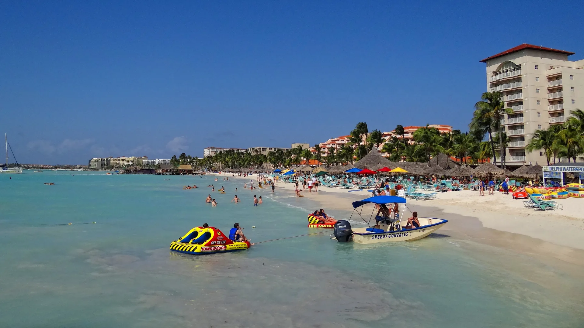 Areia branca, mar turquesa e hotéis de Palm Beach vistos do píer, em Aruba