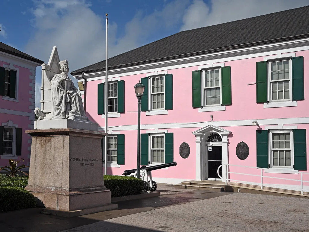 Prédio cor-de-rosa da House of Assembly e estátua da Rainha Vitória na Parliament Square, em Nassau
