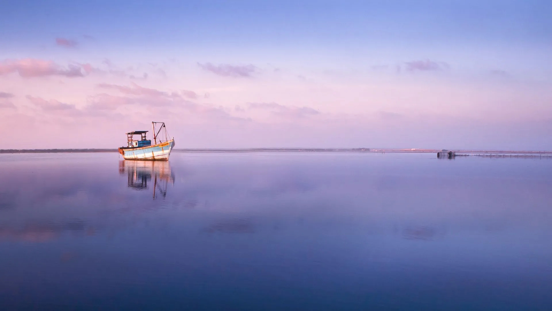 Embarcação isolada navegando em mar aberto ao entardecer