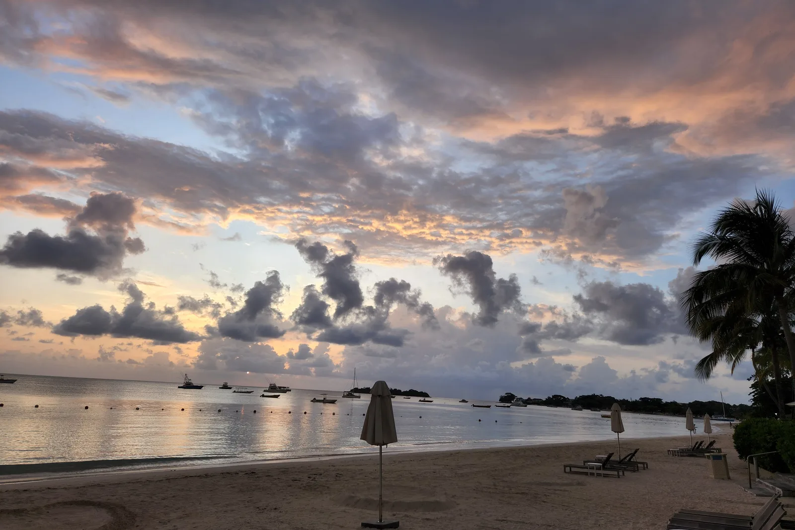 Entardecer na Seven Mile Beach, em Negril, com barcos ancorados na baía