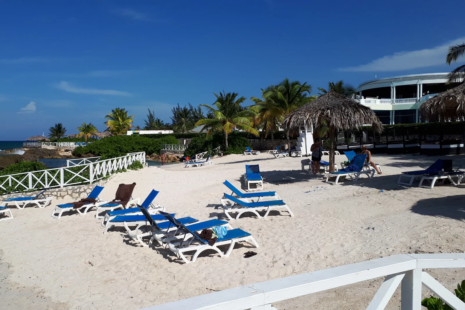 Praia de areia branca com espreguiçadeiras e coqueiros em Montego Bay