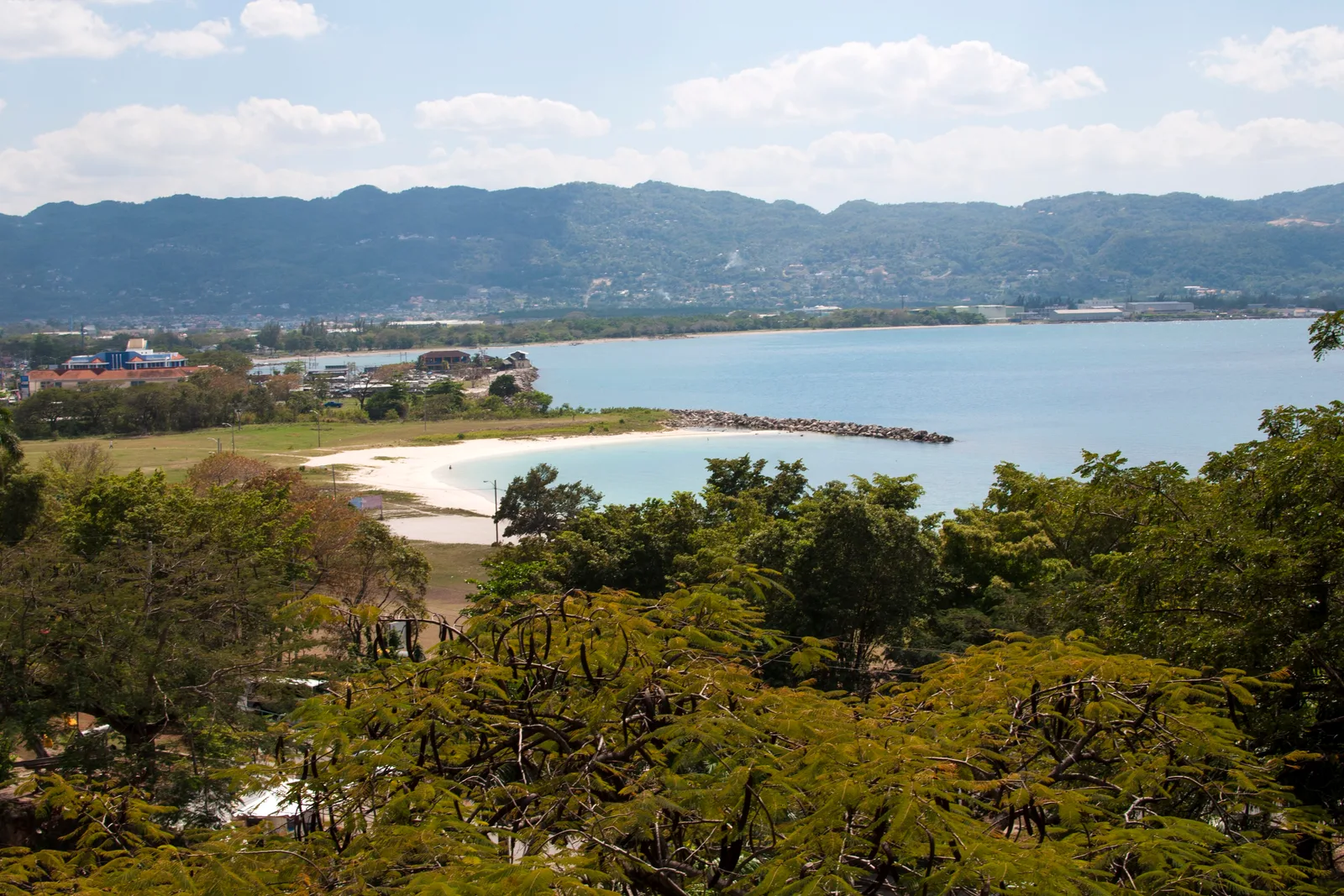 Baía de Montego Bay vista do alto, com praia de areia branca e montanhas ao fundo