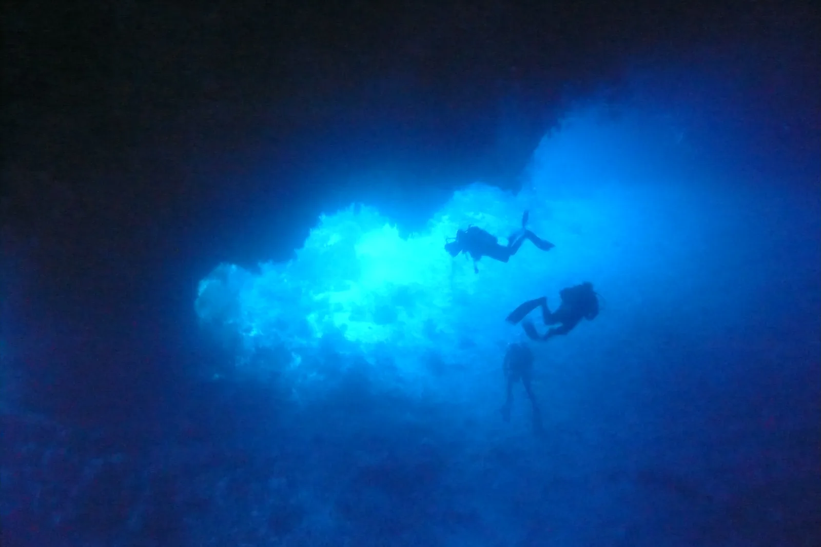 Mergulhadores contra a luz na boca do Siaes Tunnel, Palau