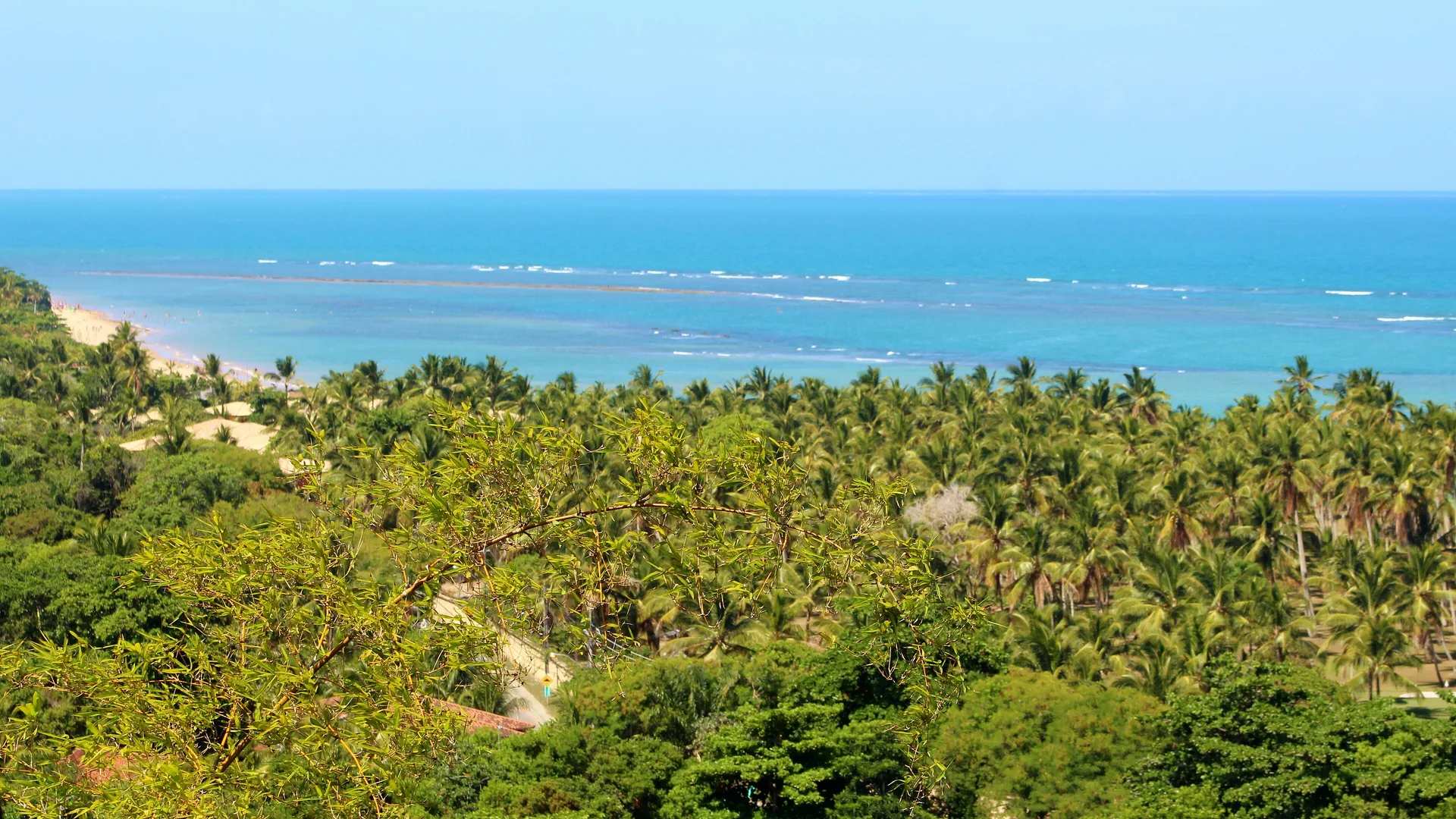Litoral de Arraial d'Ajuda visto do alto, com coqueirais e a linha de recifes ao fundo