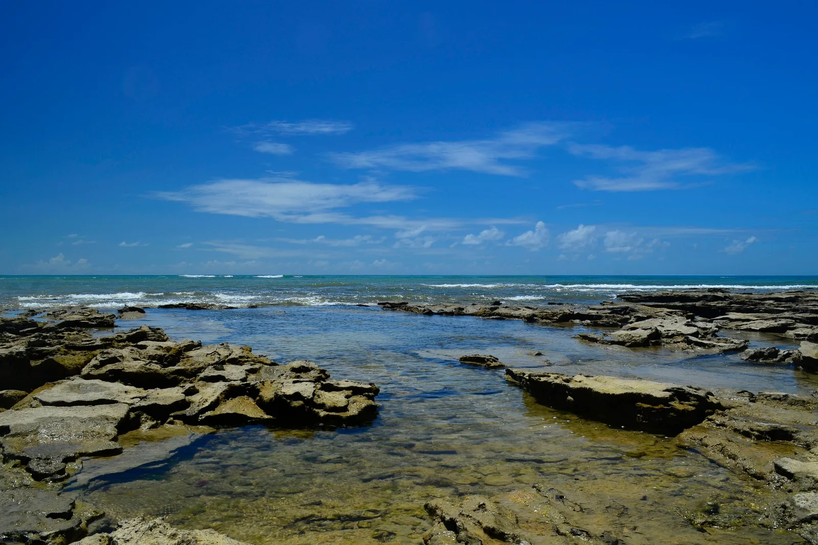 Bancada de recife e piscina natural na praia de Arraial d'Ajuda, com a maré baixa