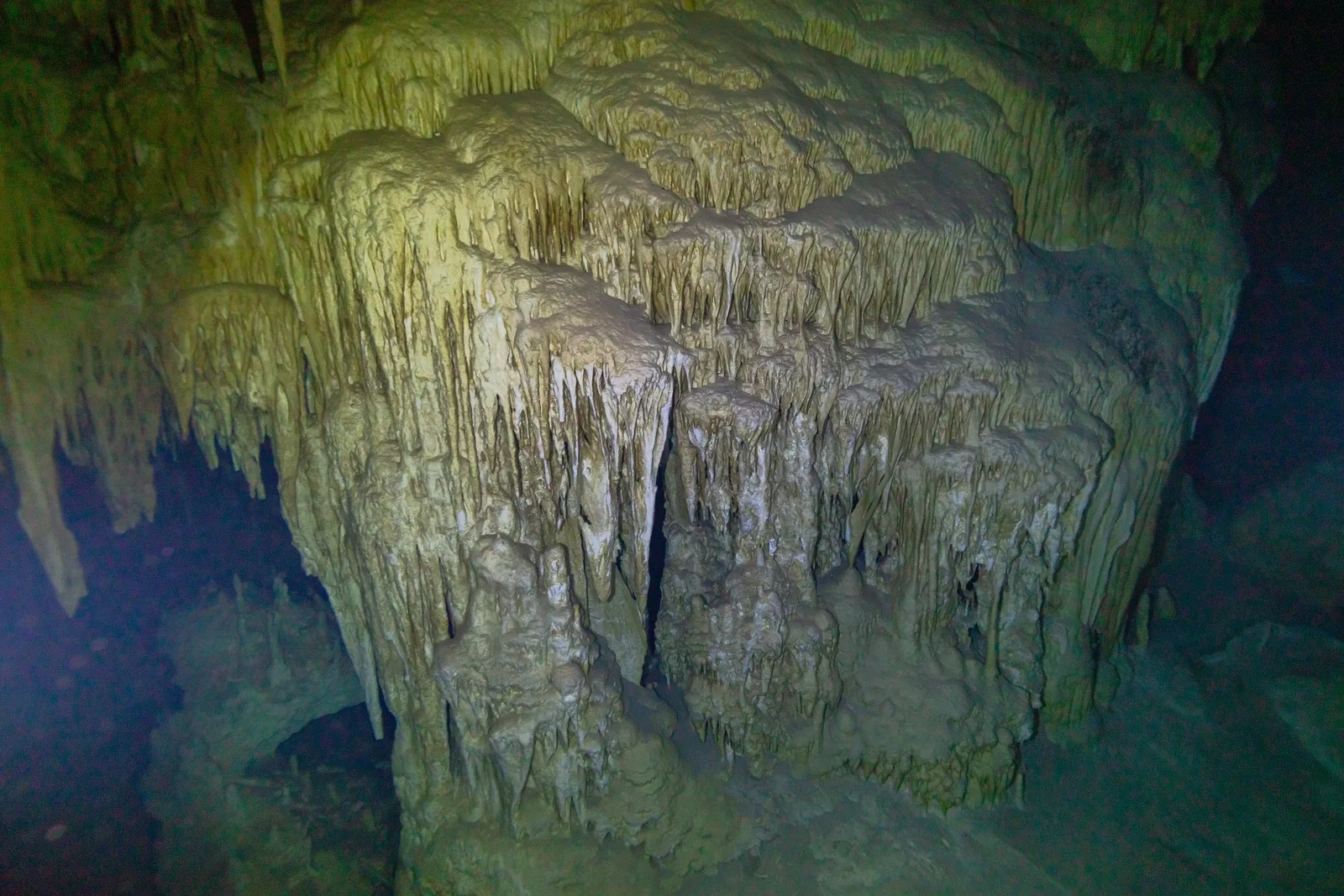 Estalactites e formações calcárias iluminadas dentro do cenote Dos Ojos