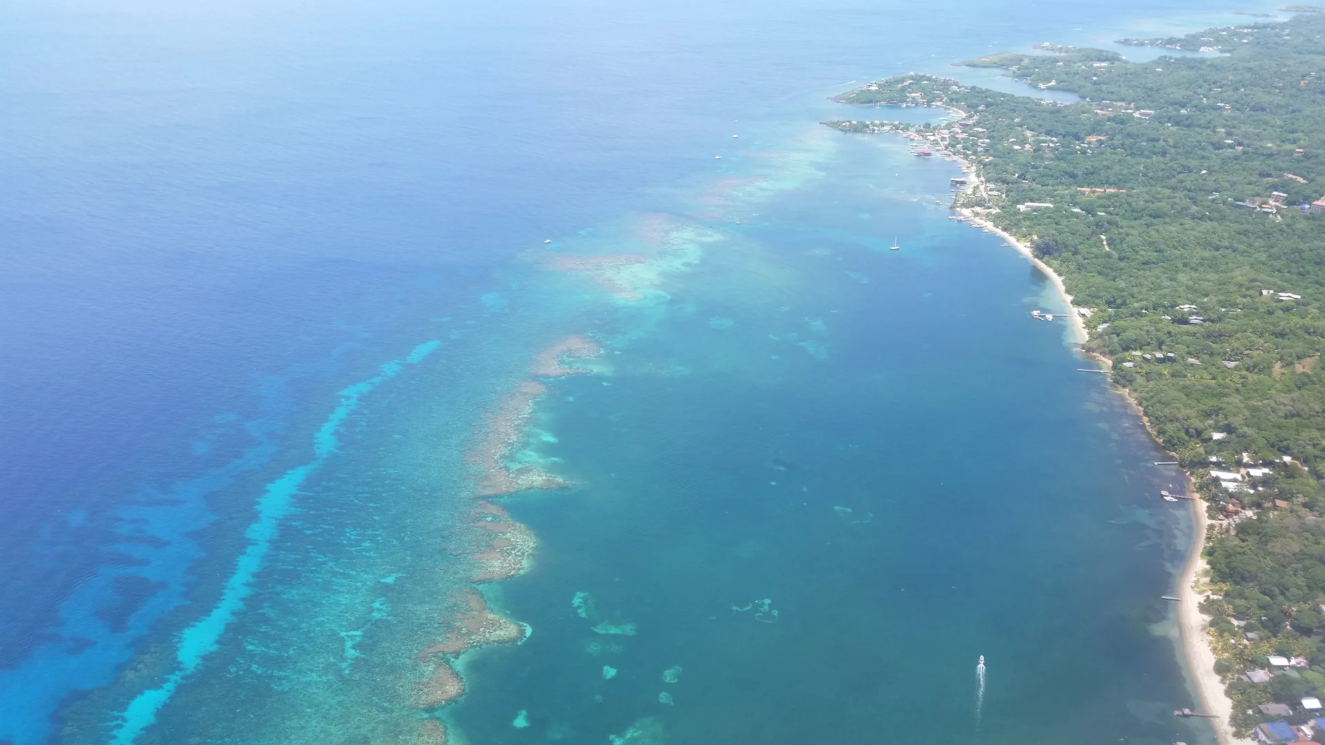 Vista aérea da costa de Roatán rumo a West End, com a barreira de corais junto à praia
