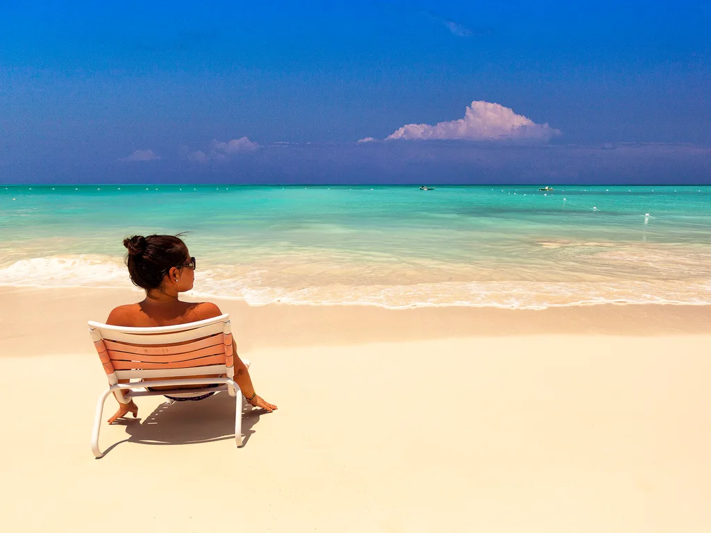 Espreguiçadeira na areia branca de Grace Bay, com o mar turquesa de Providenciales ao fundo